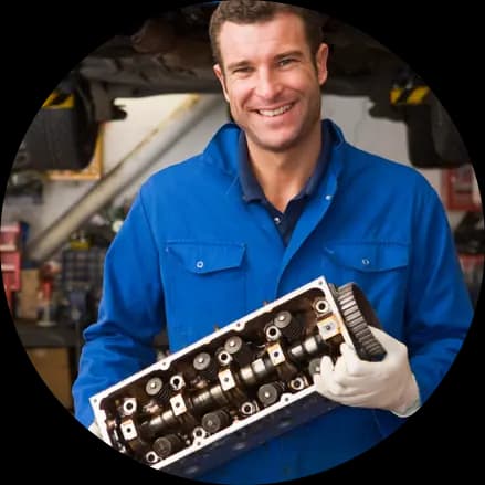 Een garagist met een cilinderkop in de hand